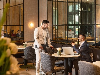 Two men in suits having a business meeting in a modern café setting.