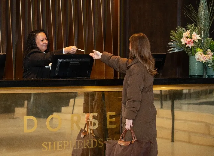 Staff giving a door key to a guest at Dorsett Shepherds Bush London the front desk .