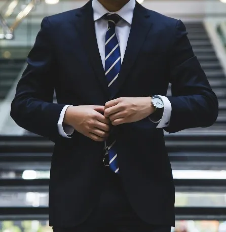 A man adjusting his suit and stair way in the background.