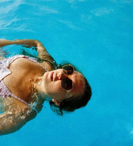 A lady wearing sunglasses in the pool.