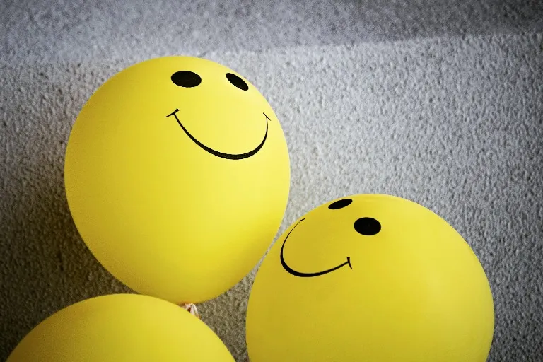 Smiley face balloons in a grey background.