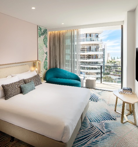 A blue chair by a twin bed at Dorsett Gold Coast Deluxe King Room