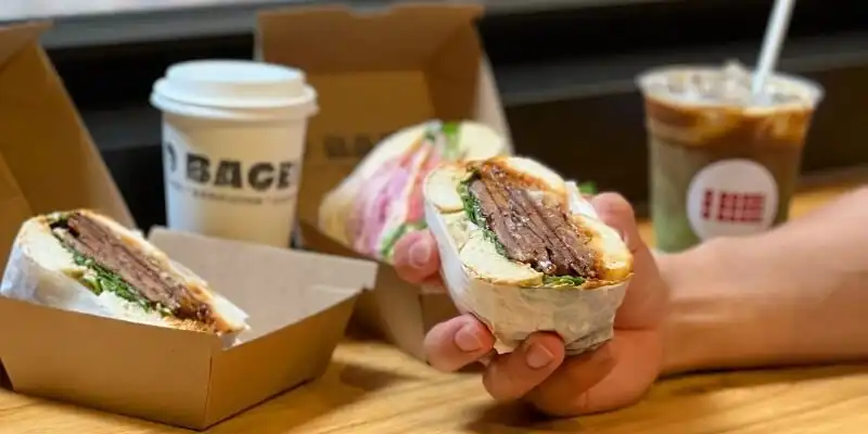 Customer holding a bagel from O Bagel Customer holding a bagel from O Bagel