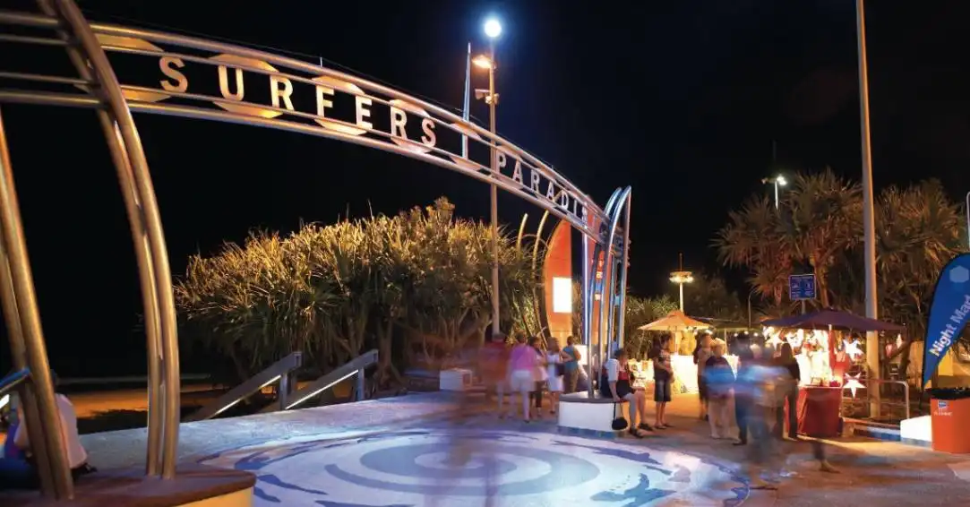 People walking through night markets under the Surfers Paradise sign