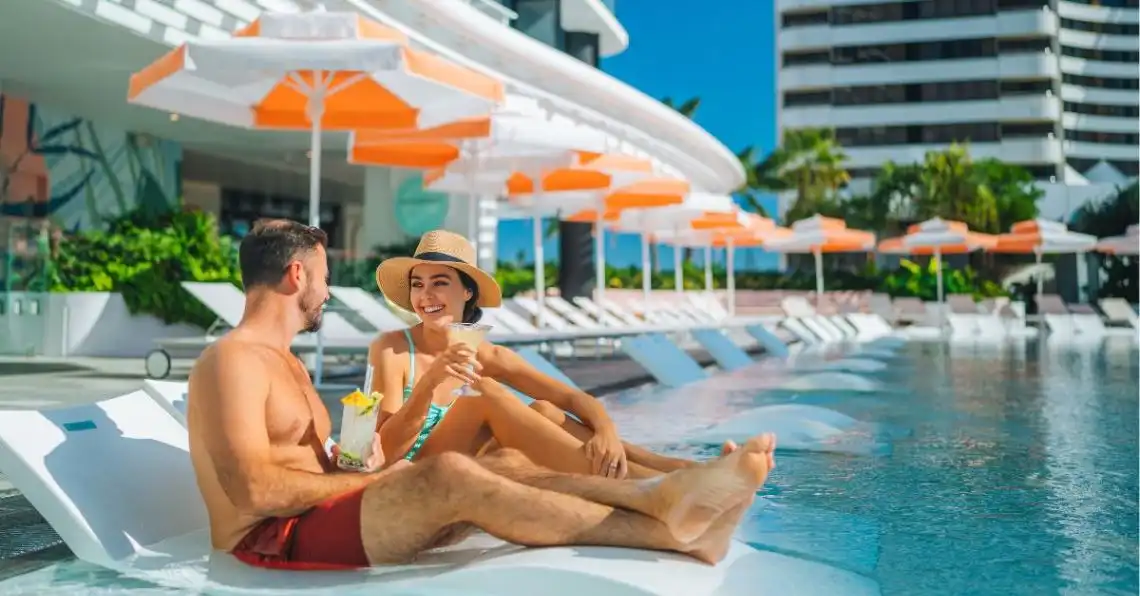 A couple relaxing the wet lounges at Isoletto Pool Club on a sunny day