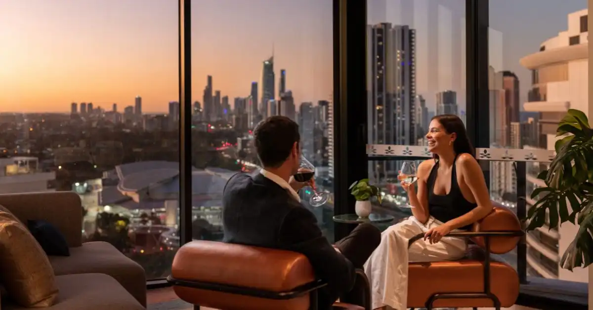 A stylish couple relax with a glass of wine in the Executive Lounge overlooking the Gold Coast at sunset