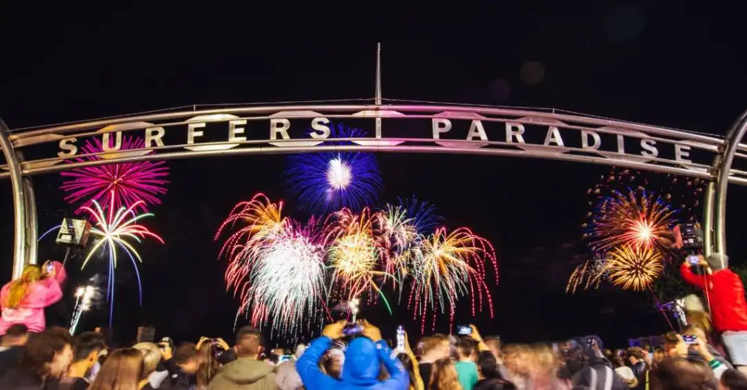 Fireworks explode off the water as crowds watch and cheer under the Surfers Paradise sign