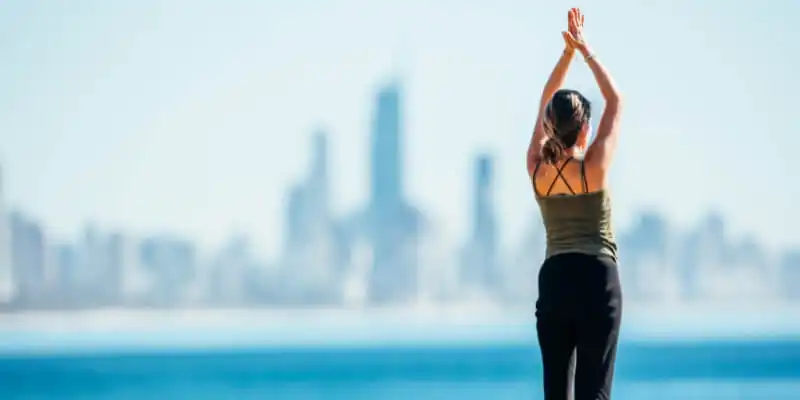 Woman doing yoga at Burleigh Heads with City Backdrop Woman doing yoga at Burleigh Heads with City Backdrop