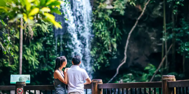 A couple on bridge near a waterfall.