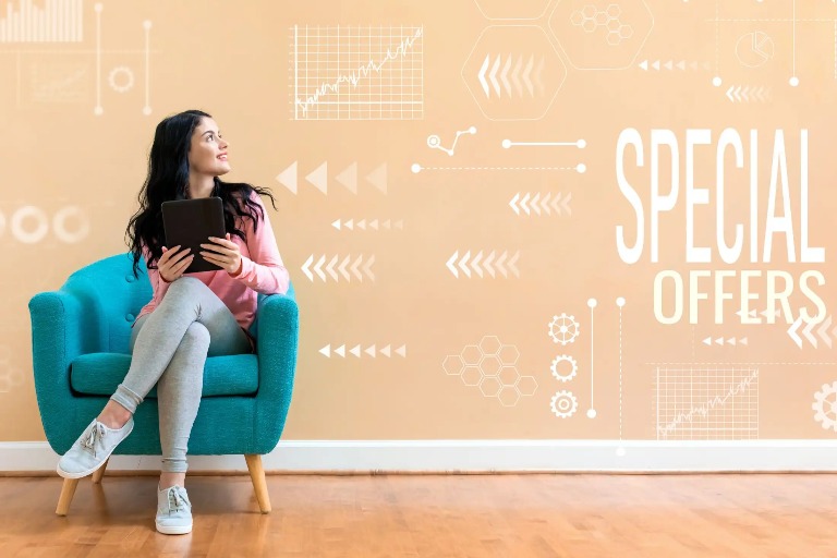 Woman on blue couch holding a laptop.