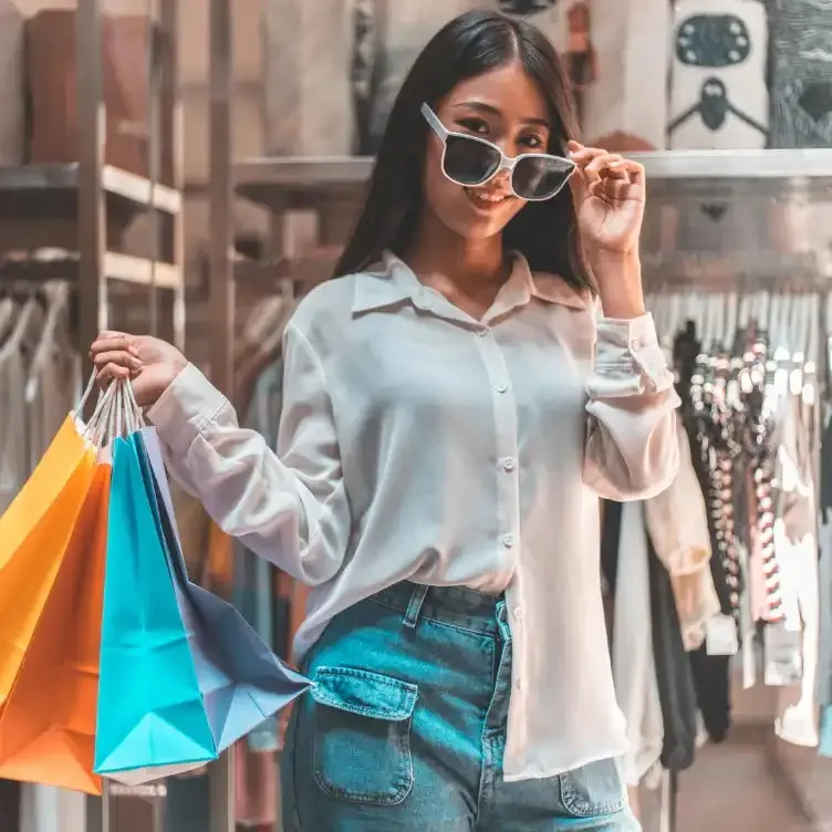 A girl carrying colourful shopping bags.