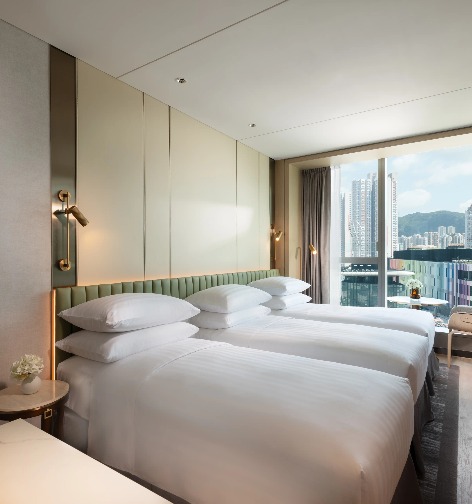 Three beds overlooking city views in a Dorsett Kai Tak Hotel Room.