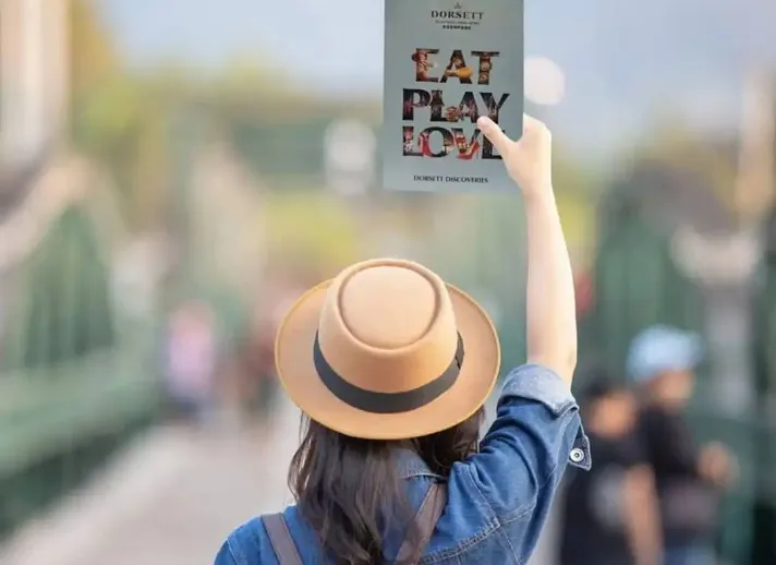 Female explorer displays Dorsett Discoveries Booklet.