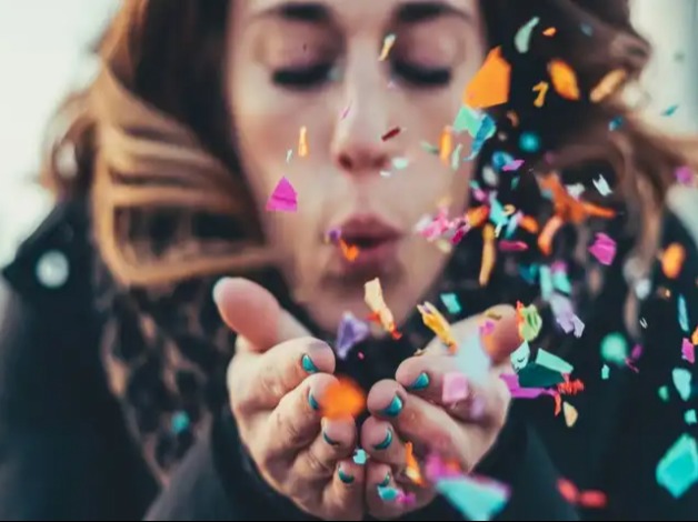 Lady blowing a handful of confetti.