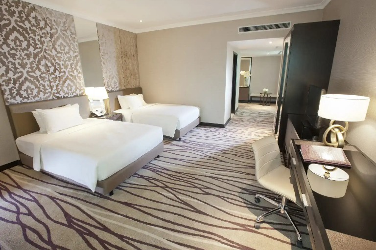 Beds, work desk and cupboard in a Dorsett Kuala Lumpur Hotel room.