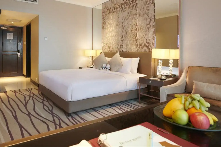 Bed, couch and a fruit basket in a Dorsett Kuala Lumpur Hotel room.