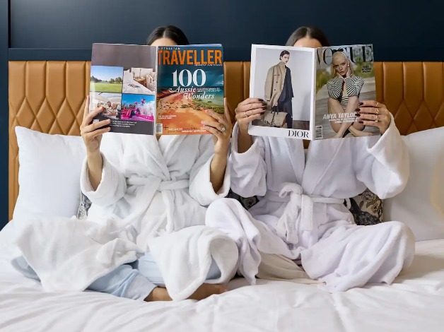 Two women reading magazines on a Dorsett Melbourne bed