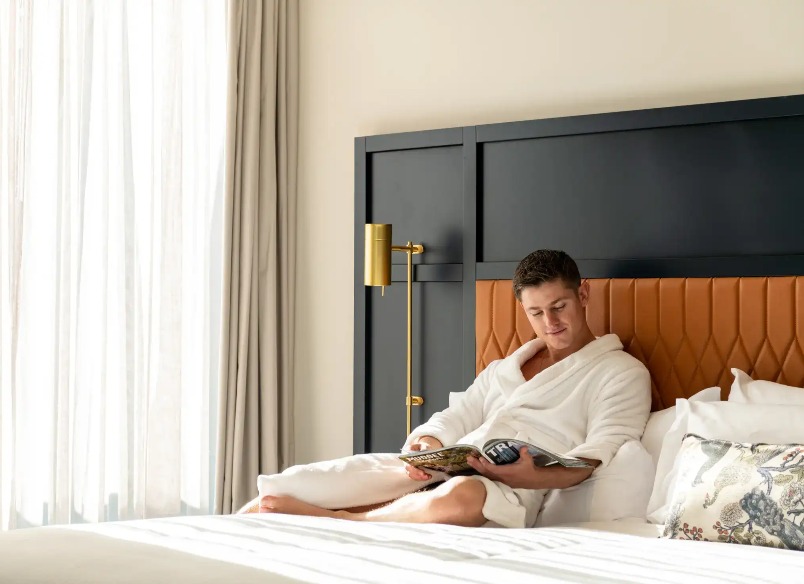 Man reading a magazine on Dorsett Melbourne Balcony Suite bed