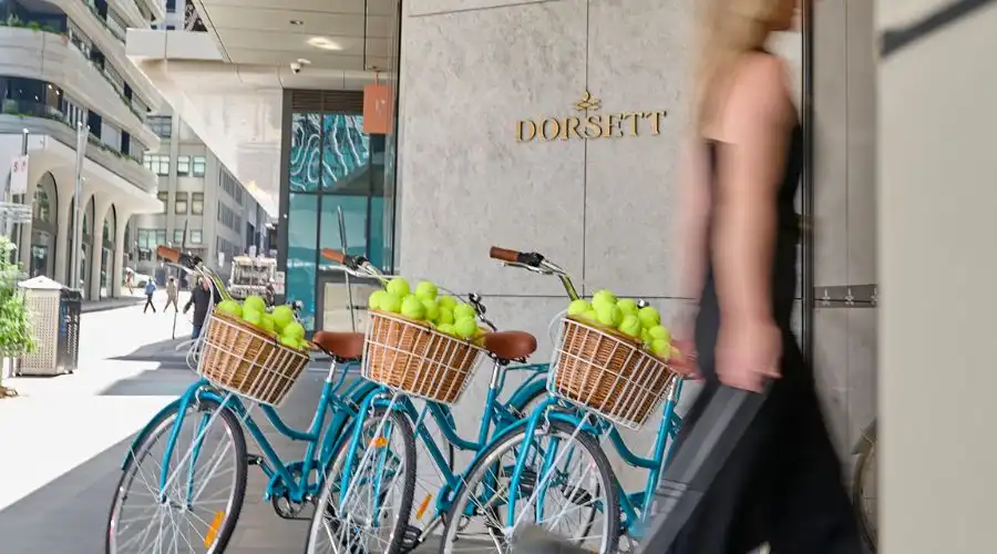 A guest enters Dorsett Hotel Melbourne where three bicycles with tennis balls line the door