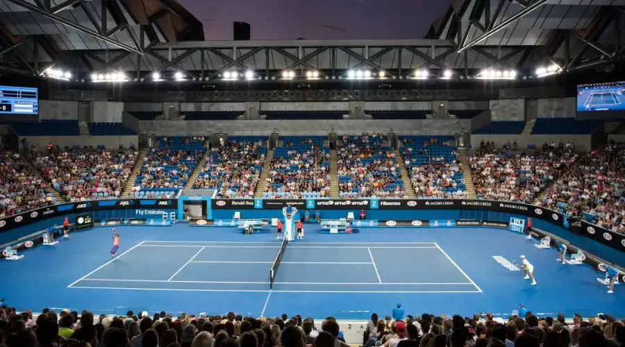 Courtside view of two tennis players on the court at night with crowds watching