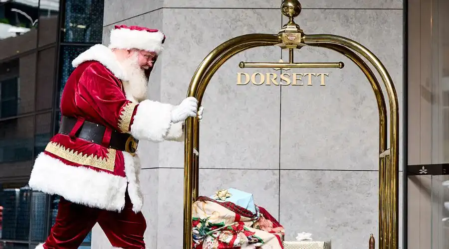 Santa pushes a luggage cart carrying Christmas presents into the lobby of Dorsett Melbourne