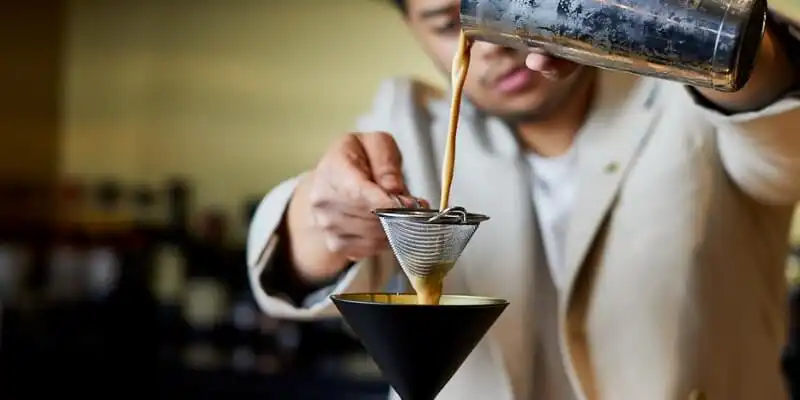 A Jin Bar mixologist pouring an espresso martini