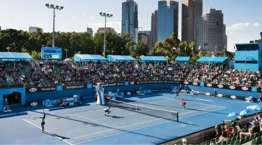 View from the crowd onto a tennis court as two players prepare for a match