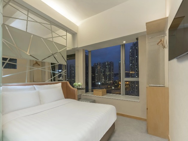 Queen-size bed with a city view in Room Executive at Dorsett Mongkok