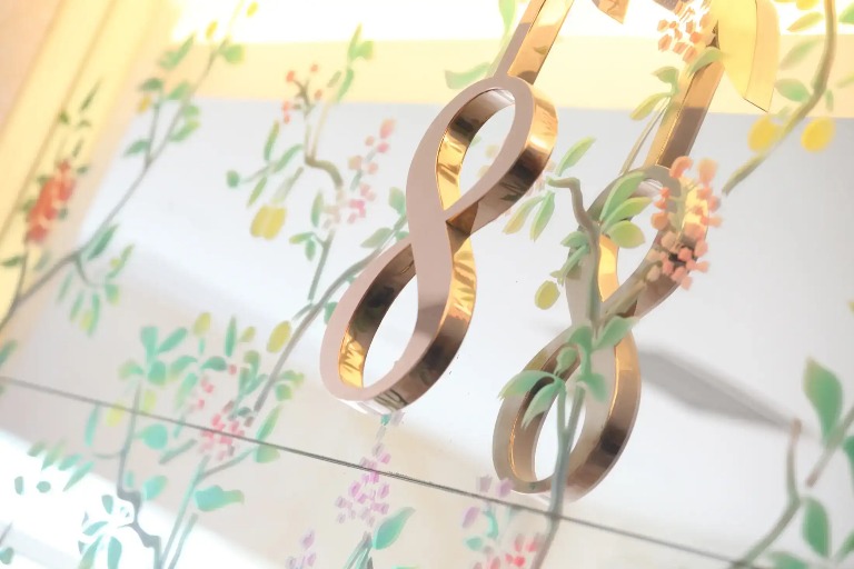 Gold infinity symbol with floral decorations in the background.