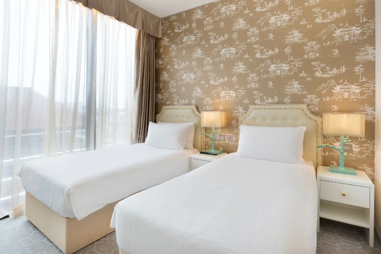 Twin beds with bedside tables for each and scenic city views from Dorsett Twin at Dorsett Shepherds Bush London Hotel