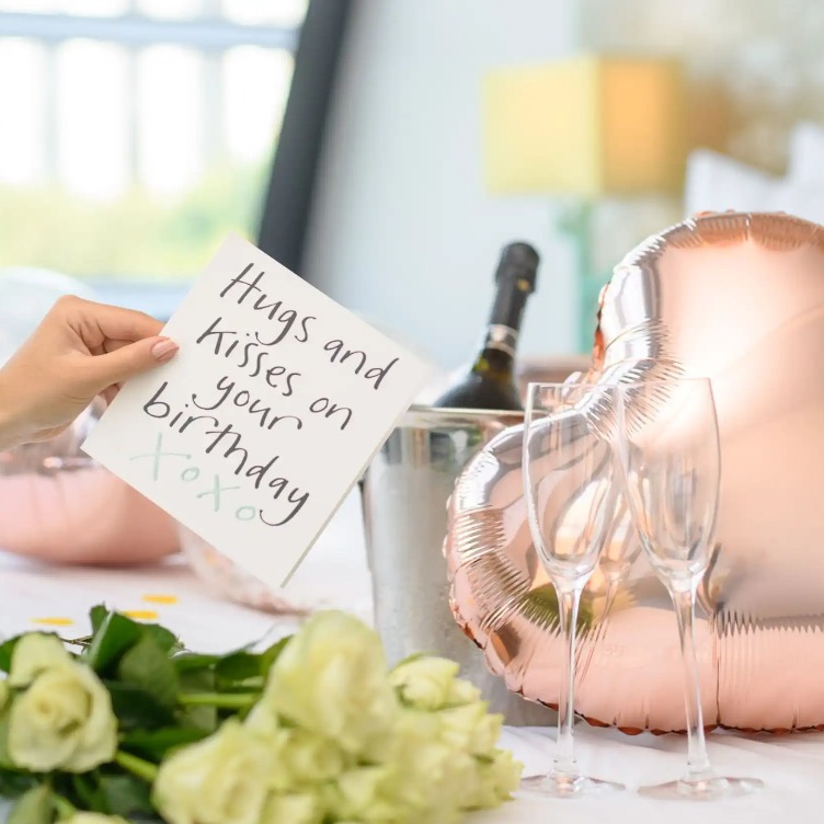 Heart-shaped balloons, flowers, champagne and glasses.