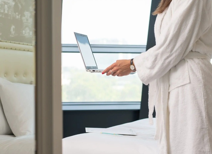 A woman holding a laptop in Dorsett Shepherds Bush London Hotel room.