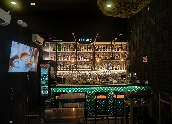 A bar counter and a shelf filled with liquor bottles in Pat's Pub.