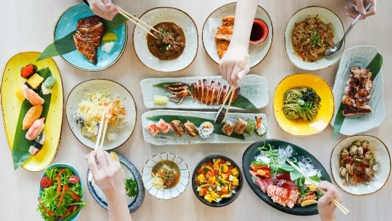 People grabbing food with chopsticks in the Senshi Sushi & Grill.