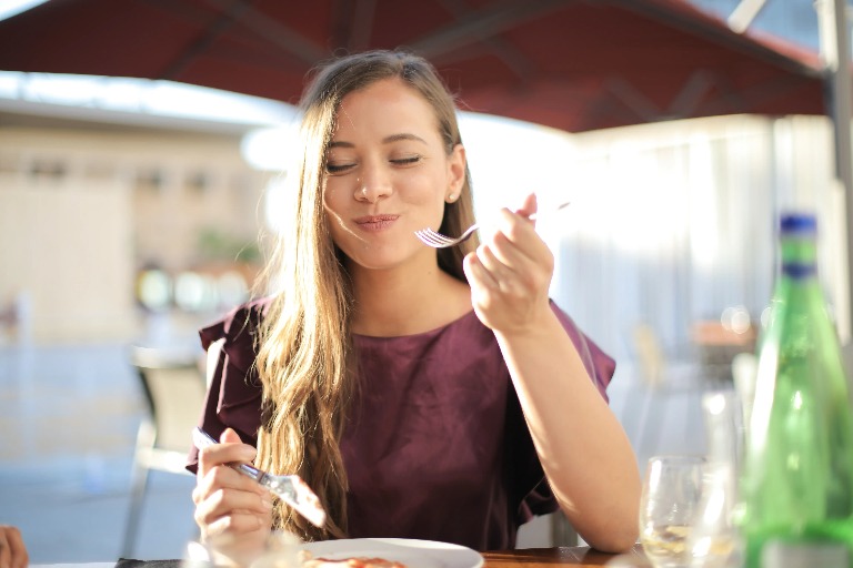 A woman eating food from a fork.