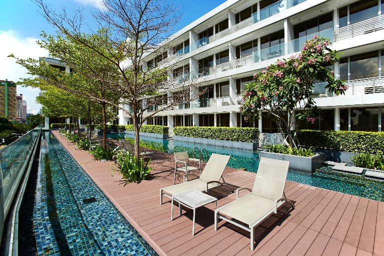 Outdoor garden with sunloungers and chairs Dorsett Singapore Hotel.