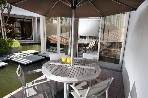 Outdoor patio with a table by a pond at Dorsett Singapore Hotel.