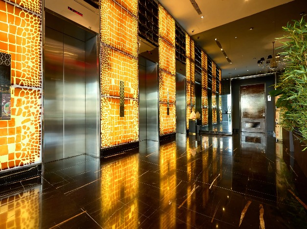 Elevators adjacent to backlit feature walls at Dorsett Singapore.