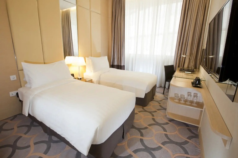 King bed, working desk and TV in the Deluxe Room at Dorsett Singapore.