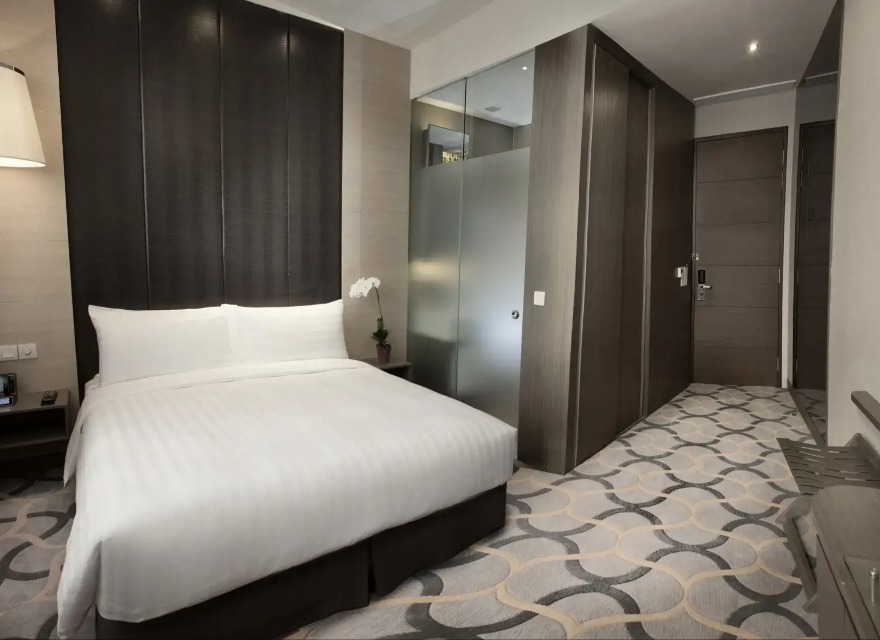 Bed by the en-suite bathroom in the Dorsett Singapore Deluxe Room.