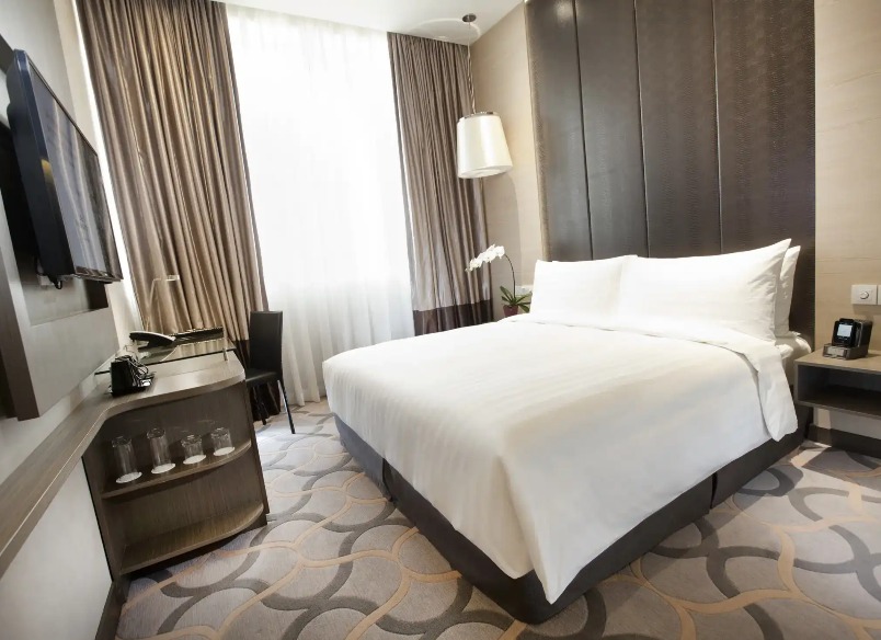 Bed, working desk, and a TV in the Dorsett Room at Dorsett Singapore.