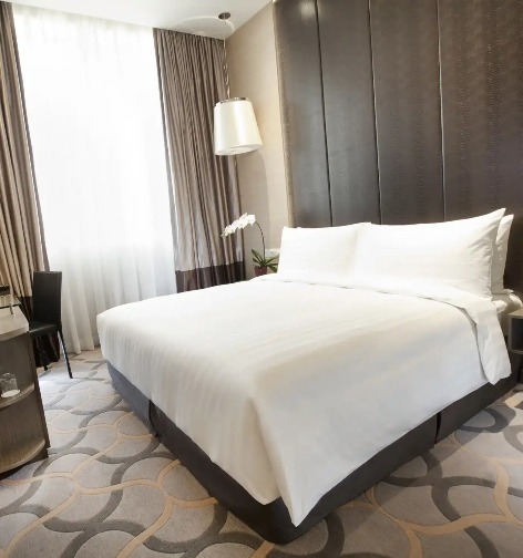 Bed, working desk, and a TV in the Dorsett Room at Dorsett Singapore.