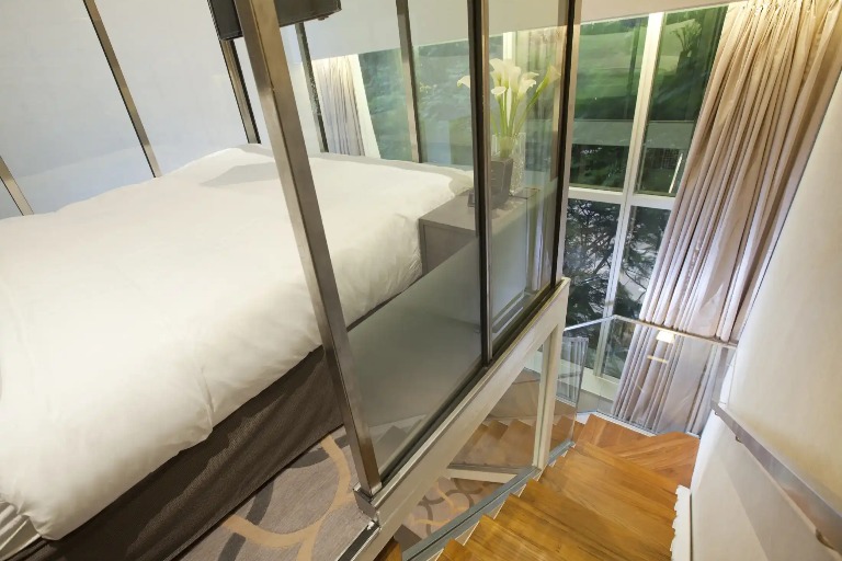 A king bed, stairway and large windows and curtains in the Loft Room.