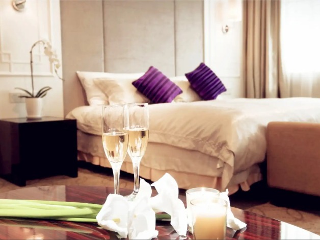 Champagne on a table by the bed in a Dorsett Wuhan Bedroom.