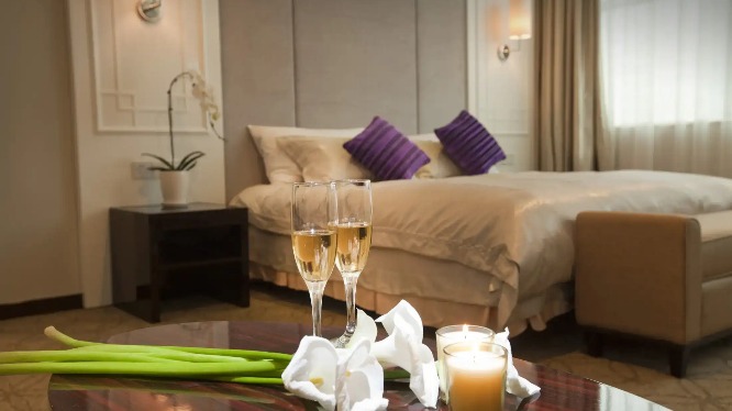 Champagne on a table by the bed in a Dorsett Wuhan Bedroom.