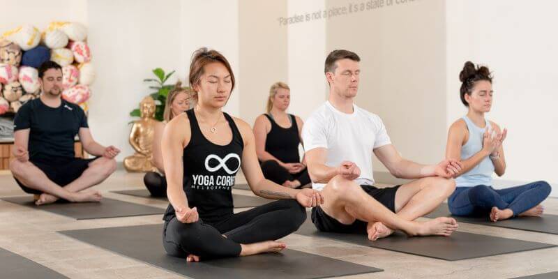 People sitting with their eyes closed in a yoga class