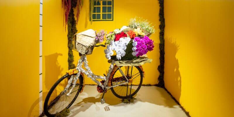 Bike with flowers art installation on yellow background